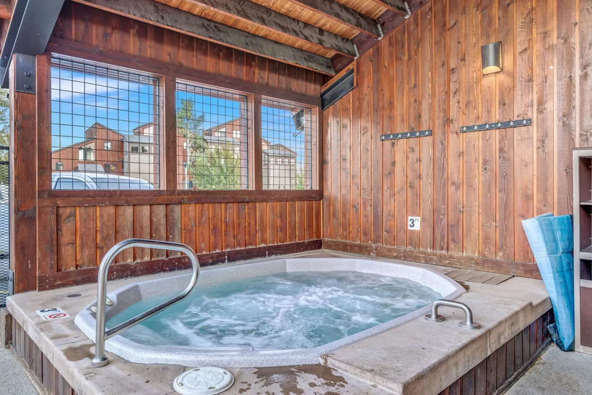 An interior hot tub space with wooden walls, large windows letting in natural light, and an overall tranquil ambience. The hot tub is central, with comfortable space for soaking and unwinding, ideal after a long day of adventure.