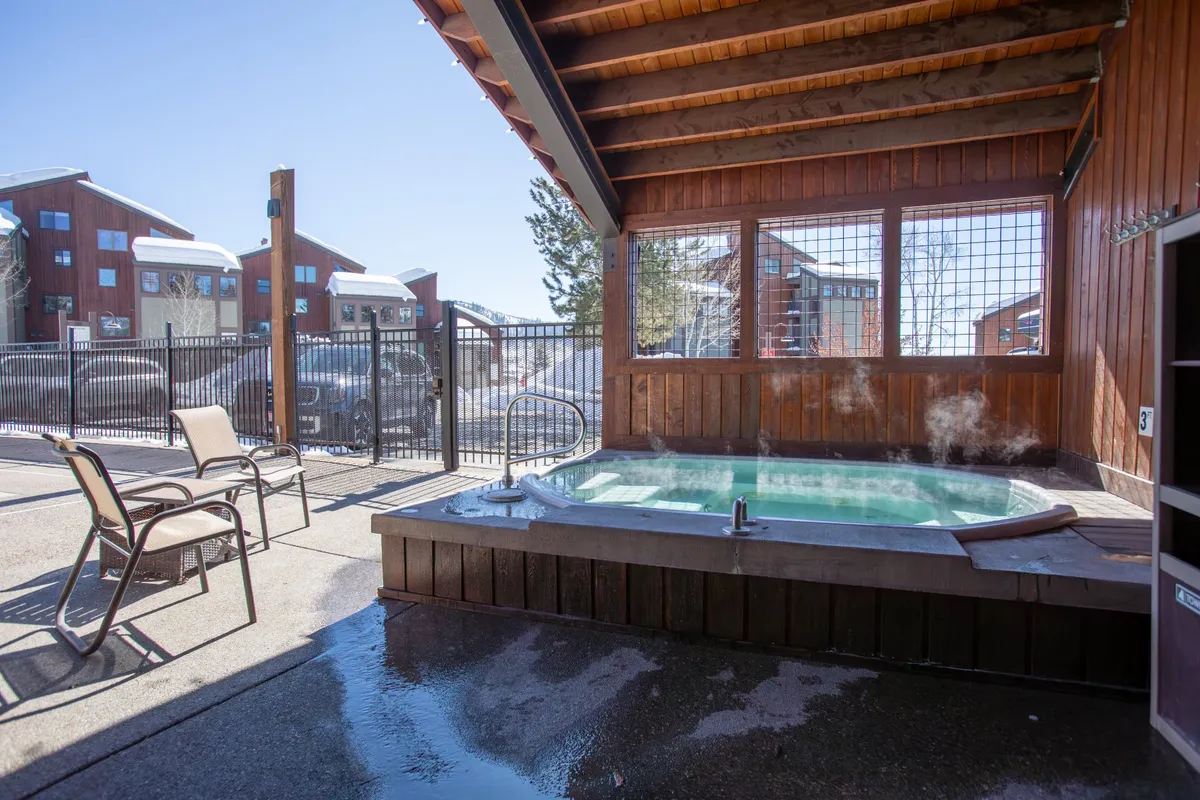 A cozy outdoor hot tub area framed by a wooden structure and surrounded by comfortable seating within a fenced enclosure. The setting is tranquil and inviting, ideal for unwinding after a day of adventure.