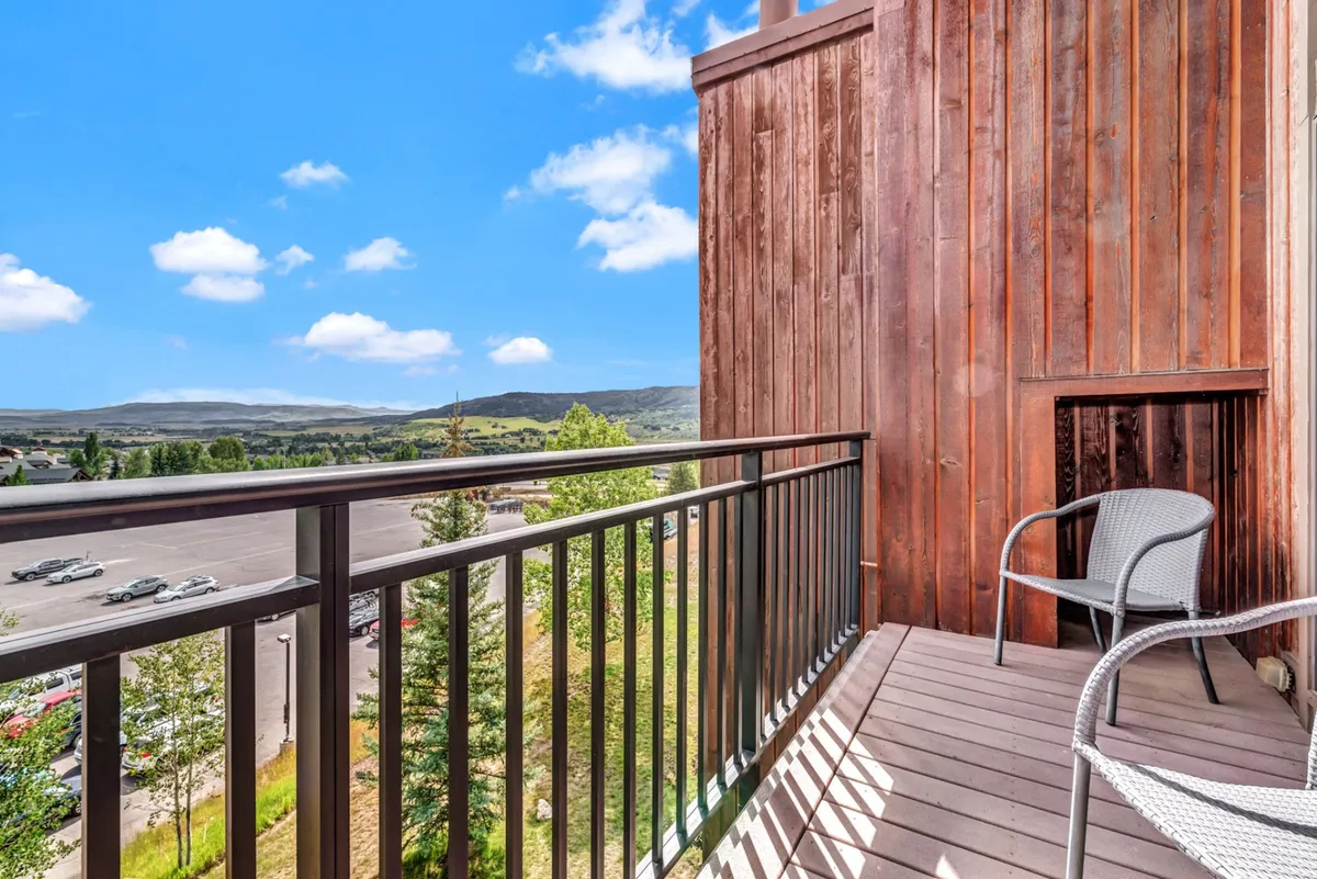 A serene balcony view with a comfortable chair overlooking a picturesque landscape. The scene invites moments of relaxation, reflection, or taking in the energy of nearby events from an elevated perspective.